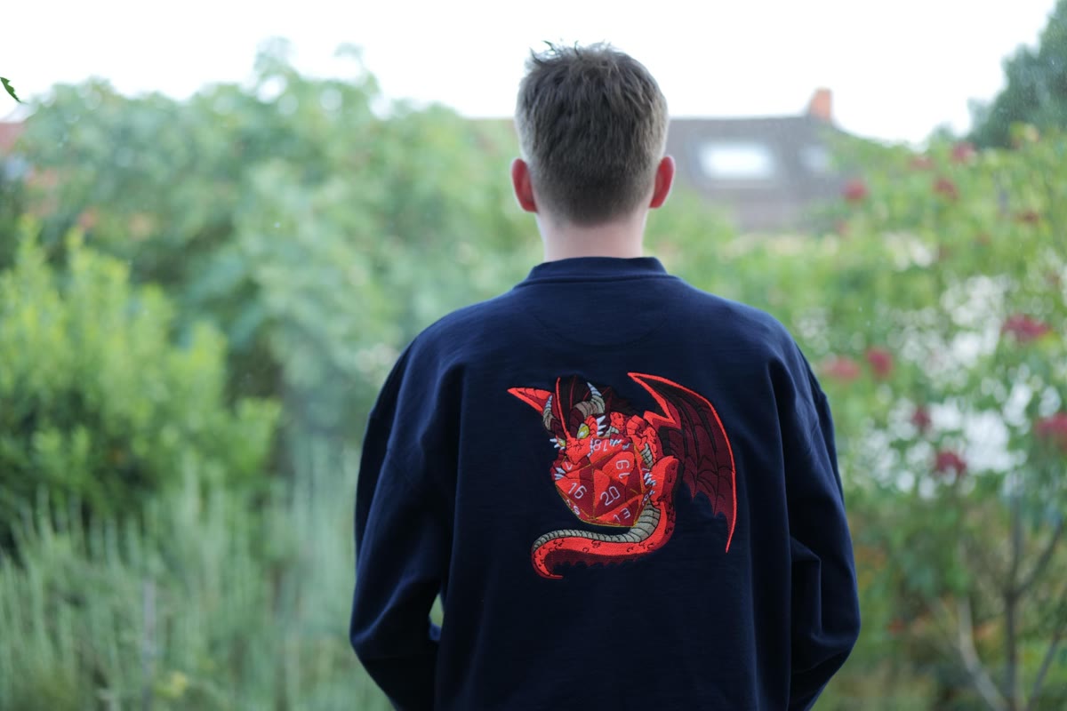 Oliver von hinten mit einer großflächigen roten Drachenstickerei auf dem Pullover